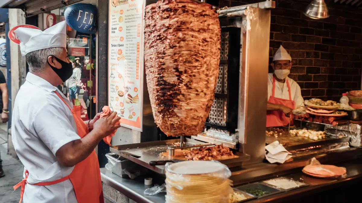 Tacos al pastor con piña, cilantro y salsa verde servidos en tortillas de maíz